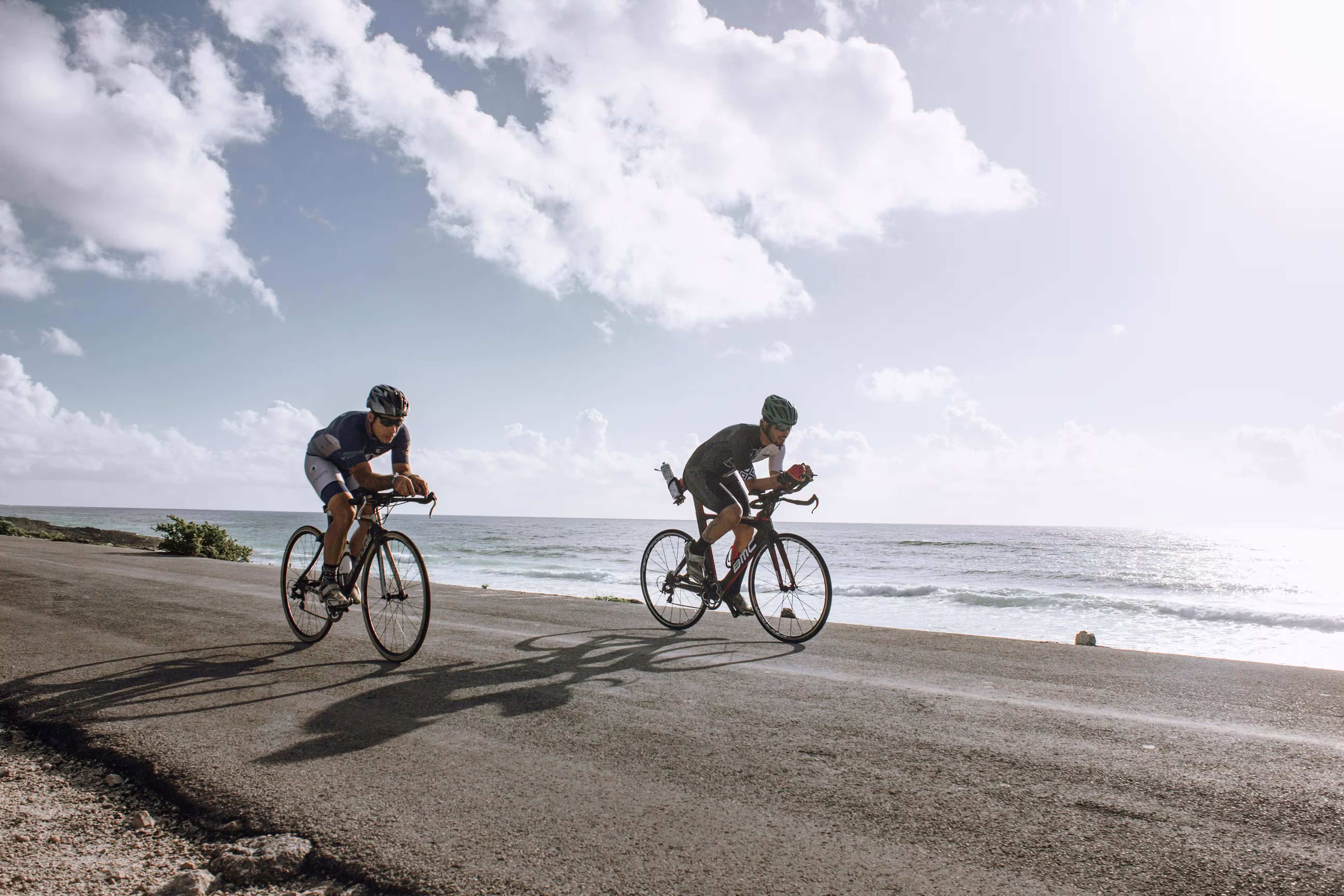 Two bikers racing side by side near the coastline